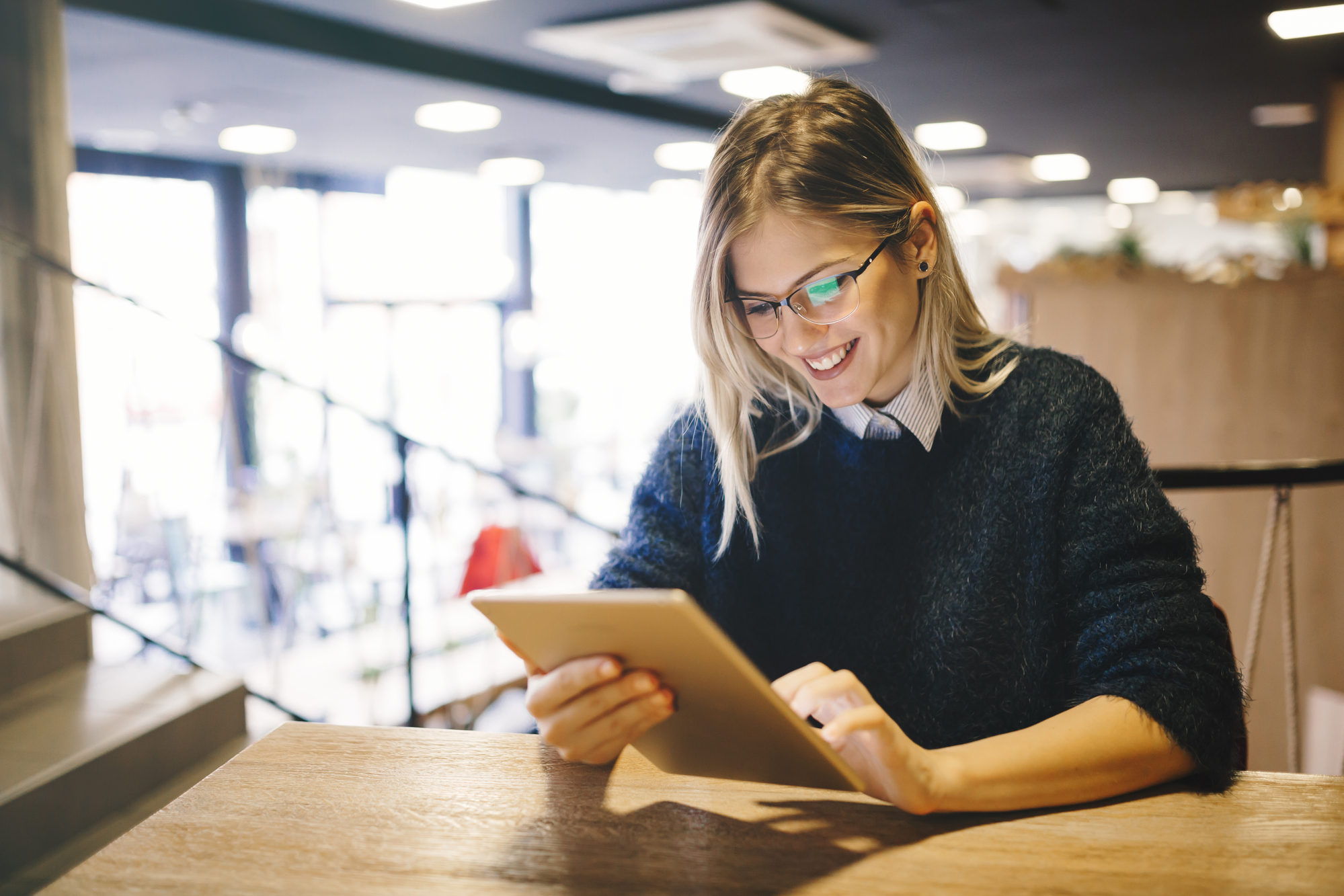Mulher sorridente com tablet nas mãos.